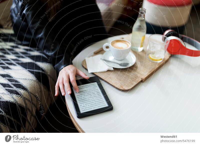 Close-up of young woman in a cafe using e-book females women E-Book ebook electronic book sitting Seated Adults grown-ups grownups adult people persons