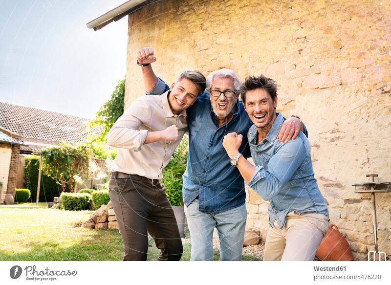Portrait of three excited men of different age embracing and cheering in garden age difference difference in age portrait portraits man males excitement
