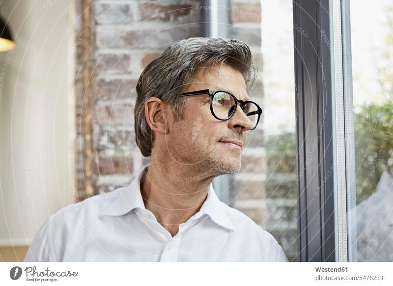Mature businessman wearing glasses looking out of window view seeing viewing Businessman Business man Businessmen Business men specs Eye Glasses spectacles