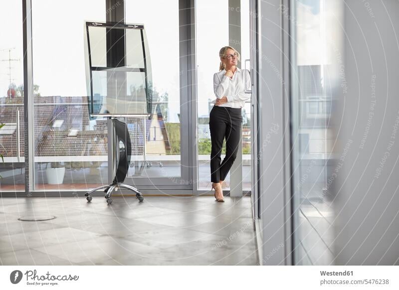 Successful businessman standing in office, looking out of window smiling smile businesswoman businesswomen business woman business women successful