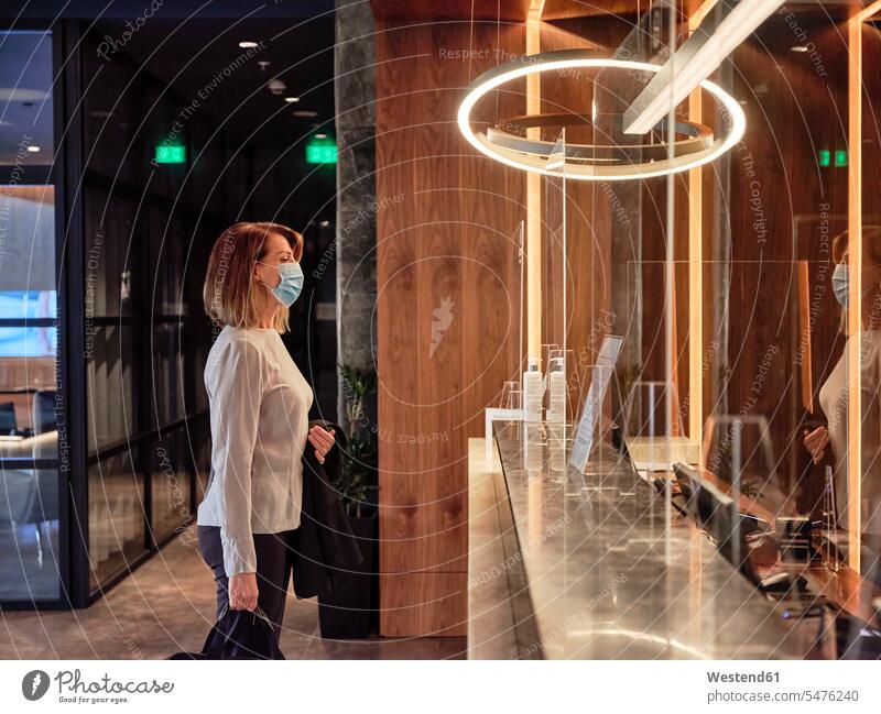 Senior woman looking at glass material while standing in hotel lobby color image colour image indoors indoor shot indoor shots interior interior view Interiors
