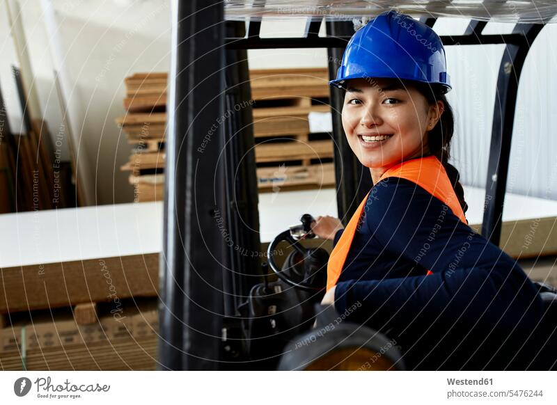 Portrait of confident female worker on forklift in factory portrait portraits factories confidence forklifts forklift truck forklift trucks female workers