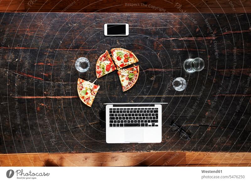 Laptop, smartphone, pizza and water glasses on tabletop, top view wooden table wood table Pizza Pizzas Water Glass Water Glasses fast food fastfood freelancer