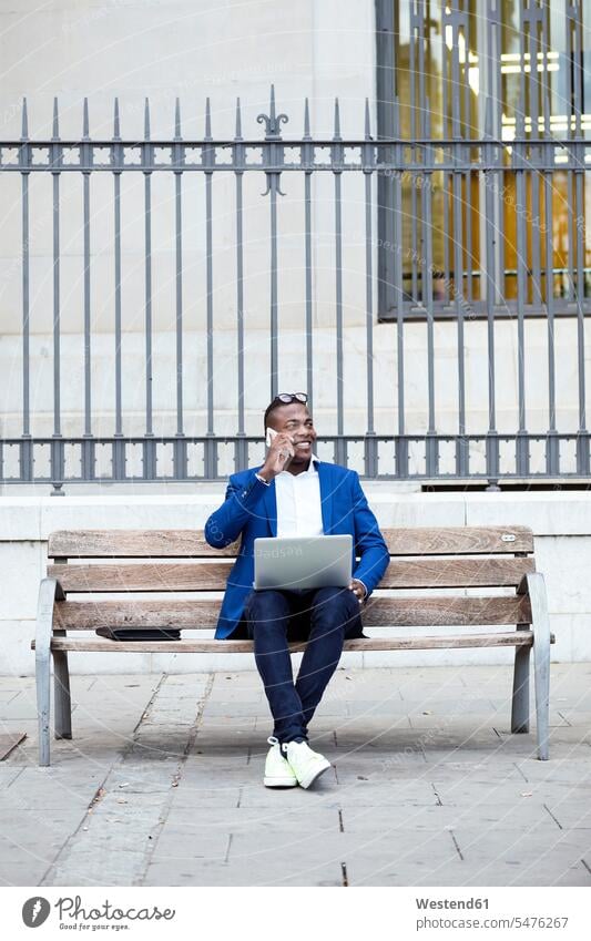 Young businessman wearing blue suit jacket sitting on bench and using smartphone human human being human beings humans person persons African black