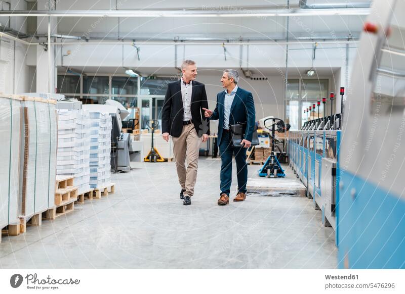 Two businessmen walking and talking in a factory business life business world business person businesspeople associate associates business associate