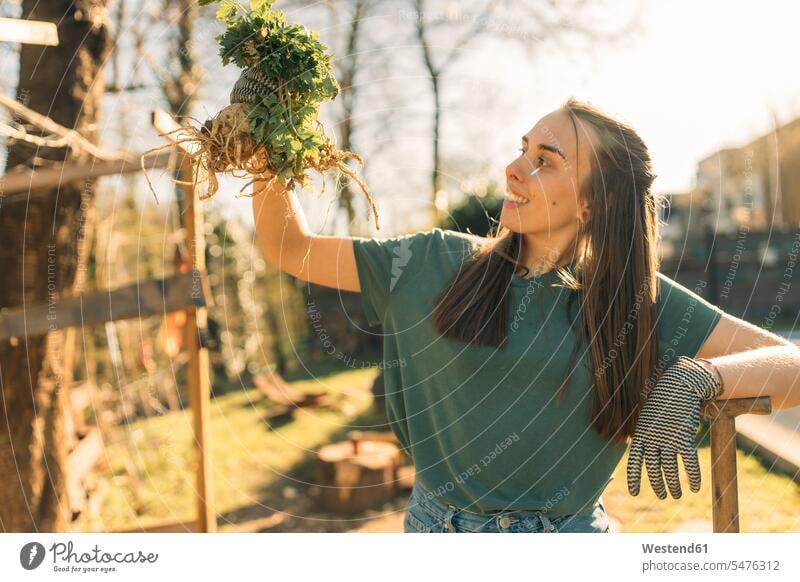 Proud young woman holding celeriac in garden smile delight enjoyment Pleasant pleasure happy passionate Contented Emotion pleased stand at home horticulture