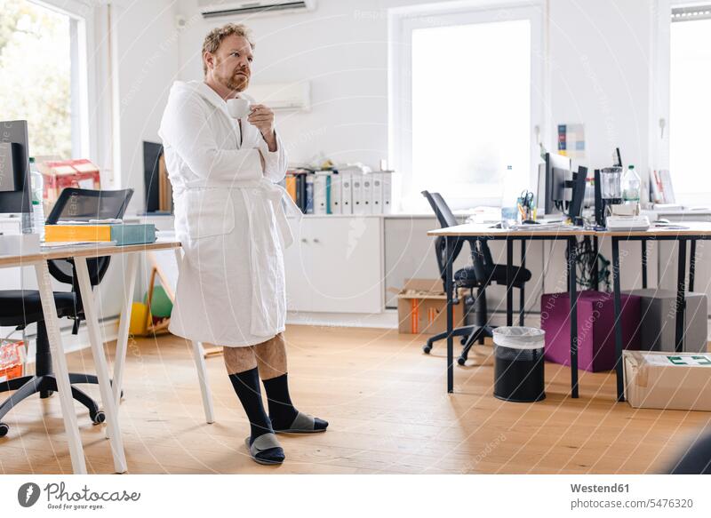 Businessman wearing bathrobe in office holding cup human human being human beings humans person persons caucasian appearance caucasian ethnicity european 1
