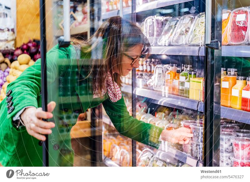 Woman taking packaged berries from cooling shelf in organic store human human being human beings humans person persons caucasian appearance caucasian ethnicity