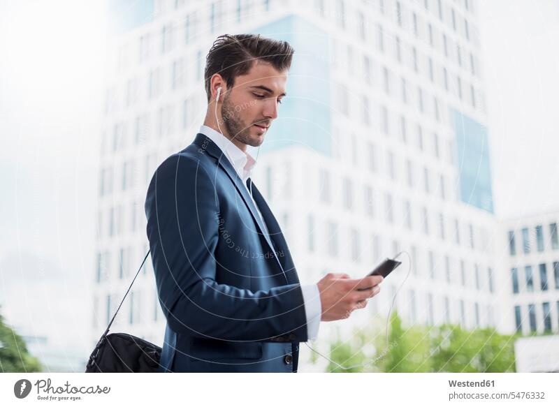 Businessman at the window with earbuds and cell phone Business man Businessmen Business men mobile phone mobiles mobile phones Cellphone cell phones