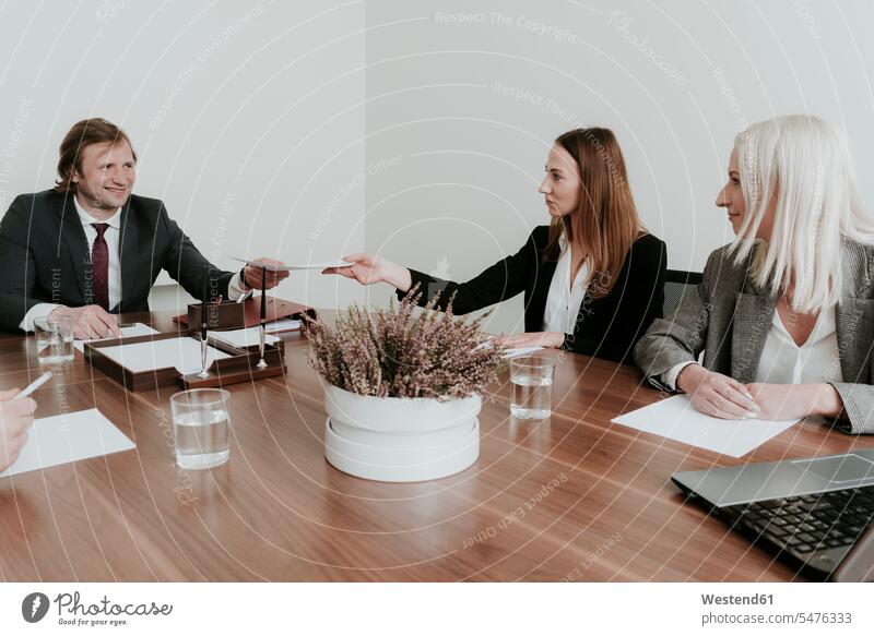 Businesswoman handing over paper to colleague during a meeting in conference room caucasian caucasian ethnicity caucasian appearance European wireless