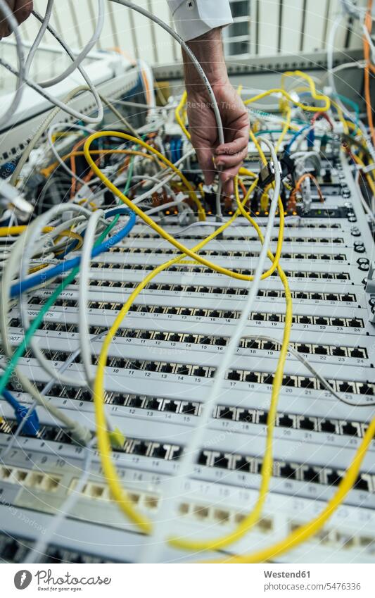 Mature man hand plugging in cable on data center rack color image colour image indoors indoor shot indoor shots interior interior view Interiors working At Work