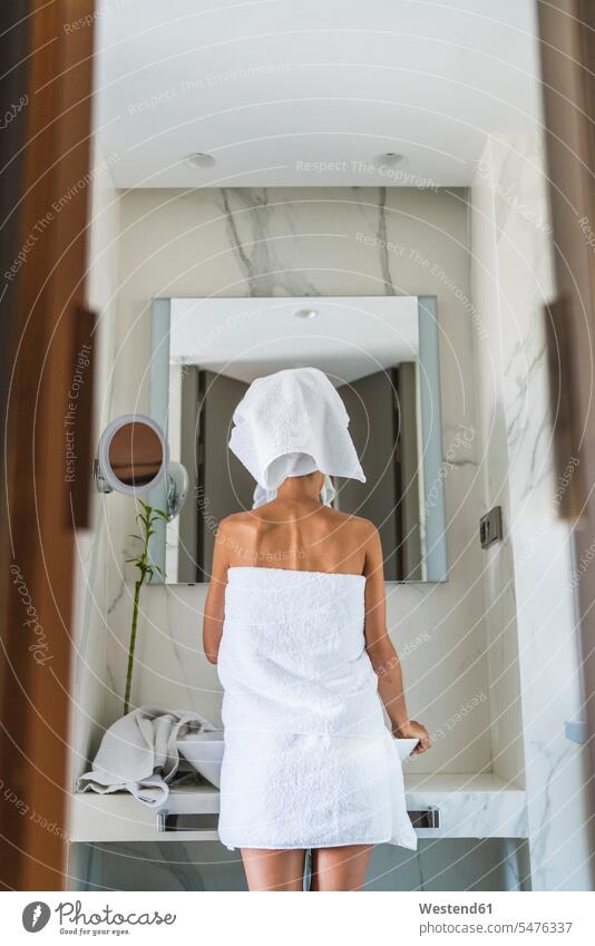 Woman wrapped in towels looking in bathroom mirror Wrapped in a towel Bath turban Turbans woman females women mirrors view seeing viewing Adults grown-ups