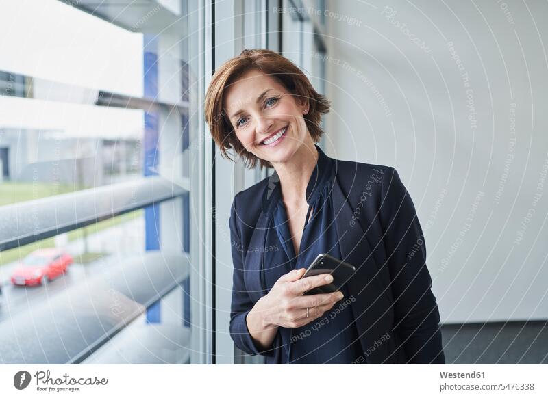 Portrait of confident businesswoman at the window holding cell phone Occupation Work job jobs profession professional occupation business life business world