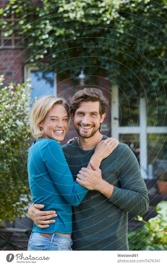 Portrait of happy couple in garden of their home house houses twosomes partnership couples gardens domestic garden happiness at home portrait portraits people
