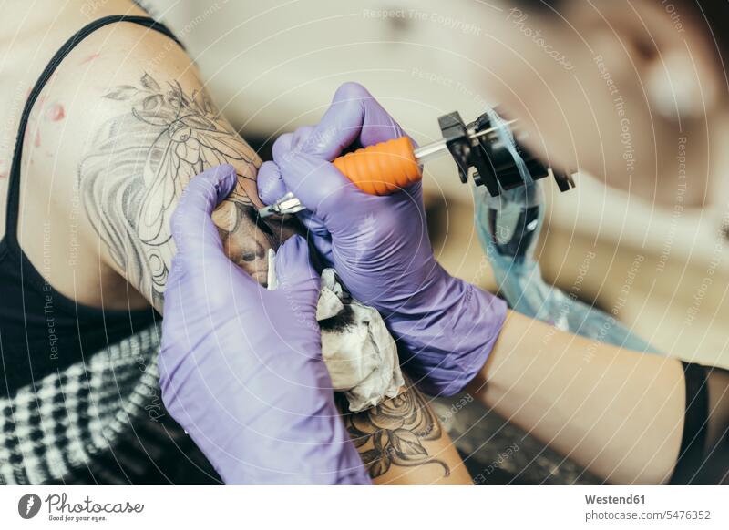 female tattooist tattooing upper arm of female customer ache Changes Changing Occupation Work job jobs profession professional occupation nonconformity