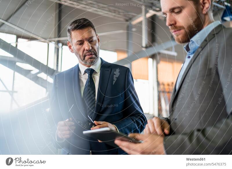 Two businessmen with tablet having a meeting in a factory colleague Occupation Work job jobs profession professional occupation superior supervisor the boss
