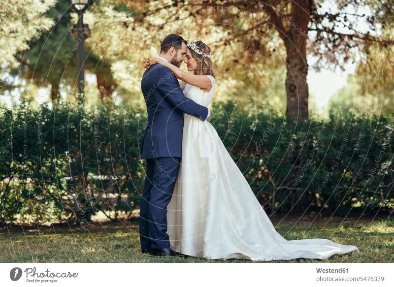 Bridal couple standing head to head with eyes closed in a park parks bridal couple bridal couples married couple married couples marriage people persons
