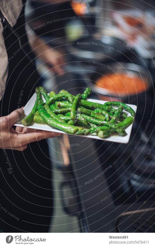 Chef holding plate with green asparagus in restaurant kitchen Occupation Work job jobs profession professional occupation Chefs cook cooks dish dishes Plates
