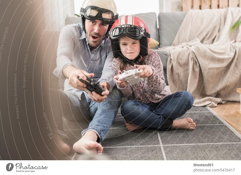 Young man and little girl wearing biker helmets, playing racing game with gaming consoles Germany Quality Time Single Father one parent video game video games