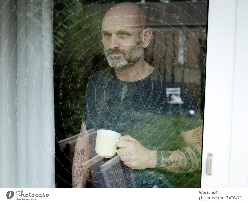 Tattooed man drinking coffee, looking out of window home at home Coffee Looking Through Window Looking Through A Window looking through glass tattooed Drink
