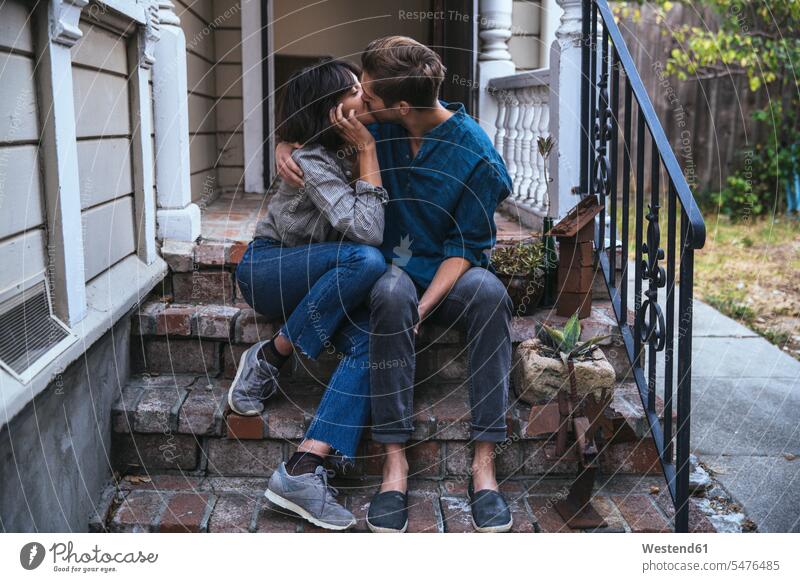 Couple sitting on stoop kissing Seated couple twosomes partnership couples kisses house entrance front stoop people persons human being humans human beings