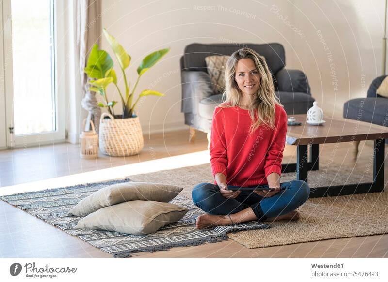 Portrait of smiling woman sitting on the floor at home holding tablet floors Seated smile females women digitizer Tablet Computer Tablet PC Tablet Computers