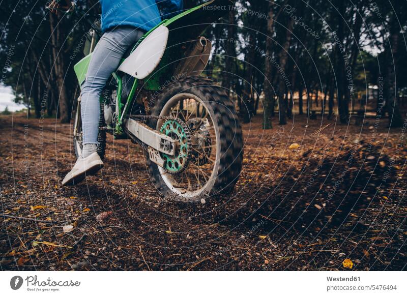 Male teenager spinning motorcycle tire while blowing dirt in forest color image colour image 16-17 years 16 to 17 years Teenager Teens people human being