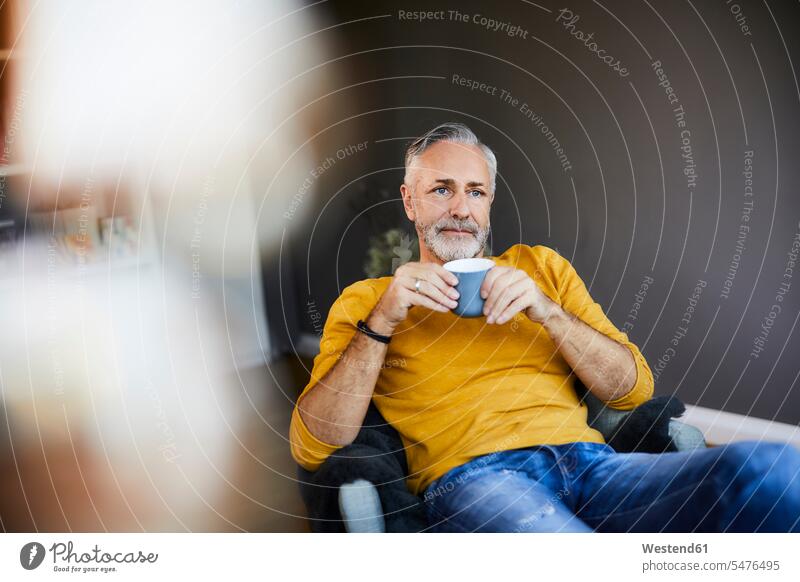 Relaxed mature man at home with cup of coffee human human being human beings humans person persons celibate celibates singles solitary people solitary person