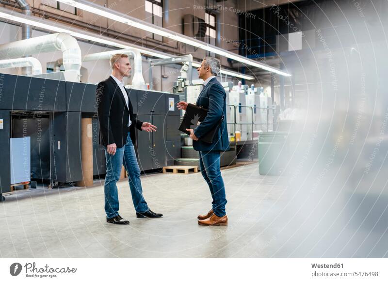 Two businessmen talking in a factory business life business world business person businesspeople associate associates business associate business associates