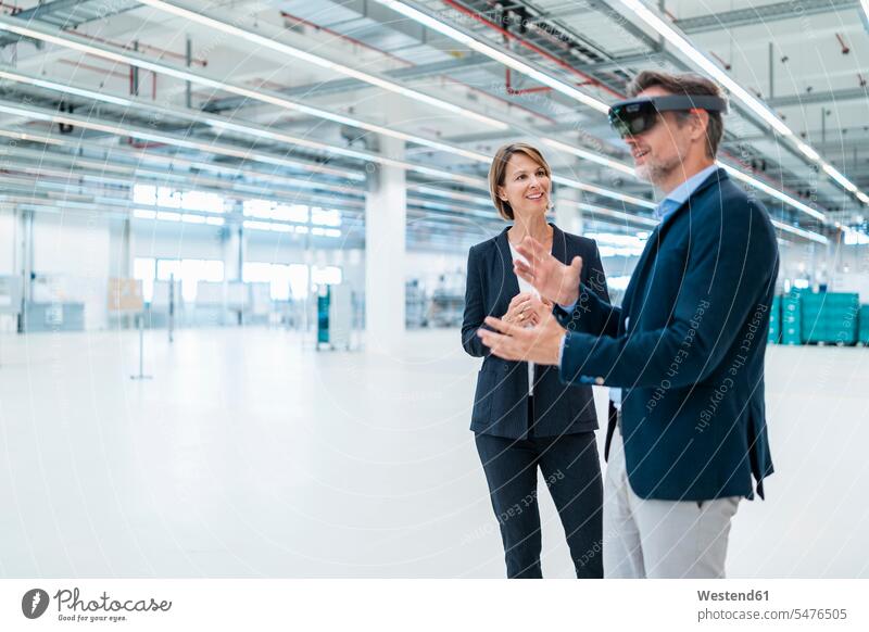 Businessman with AR glasses and businesswoman in a factory hall business life business world business person businesspeople associate associates