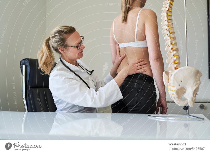 Female doctor examining back of patient in medical practice Treatment therapies consultation consultations stethoscope working At Work doctor's overall lab coat