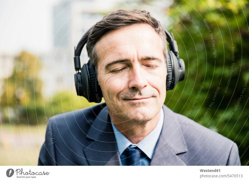 Businessman with closed eyes listening to music with headphones hearing Business man Businessmen Business men headset business people businesspeople