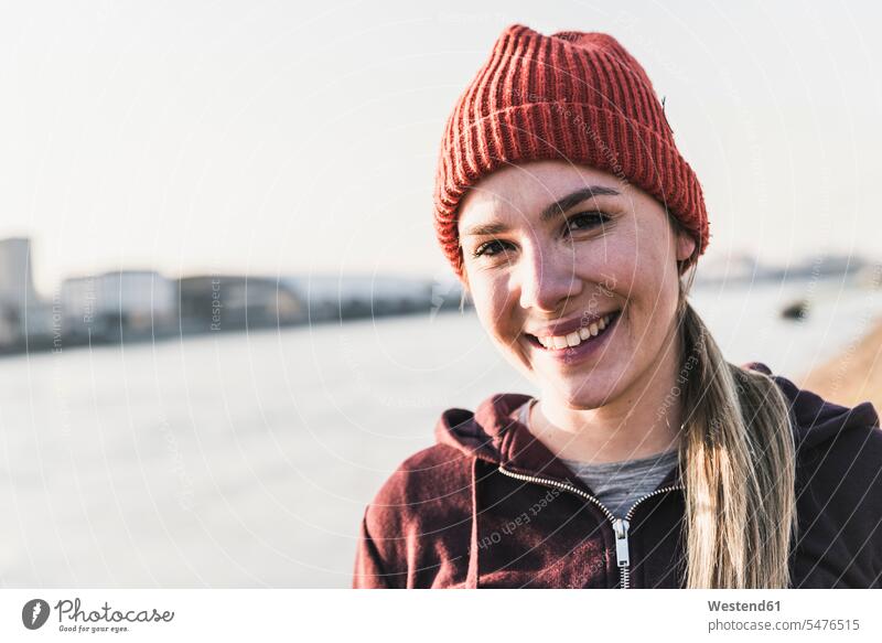 Portrait of smiling sportive young woman at the riverside in the city River Rivers riverbank sporting sporty athletic smile town cities towns portrait portraits