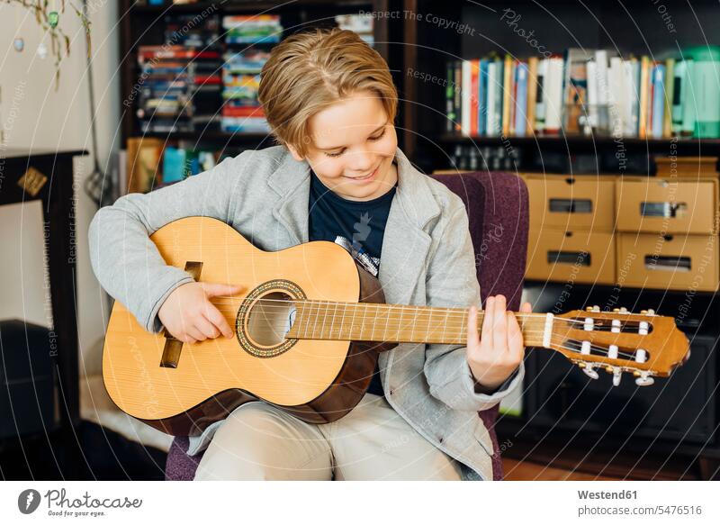 Boy playing guitar at home Instrument Instruments musical instruments stringed instruments guitars acoustic guitars classical guitar classical guitars smile