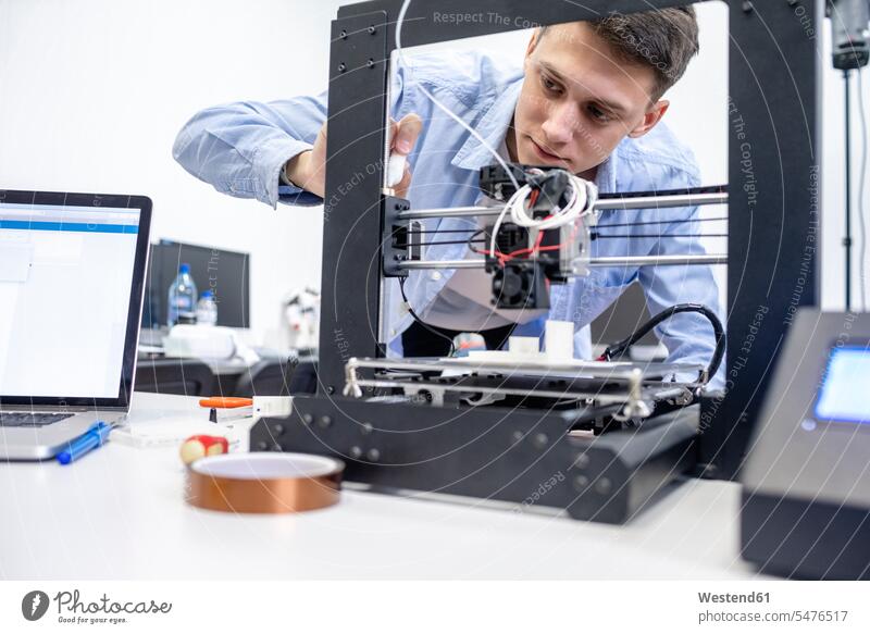 Student setting up 3D printer, using laptop human human being human beings humans person persons caucasian appearance caucasian ethnicity european 1