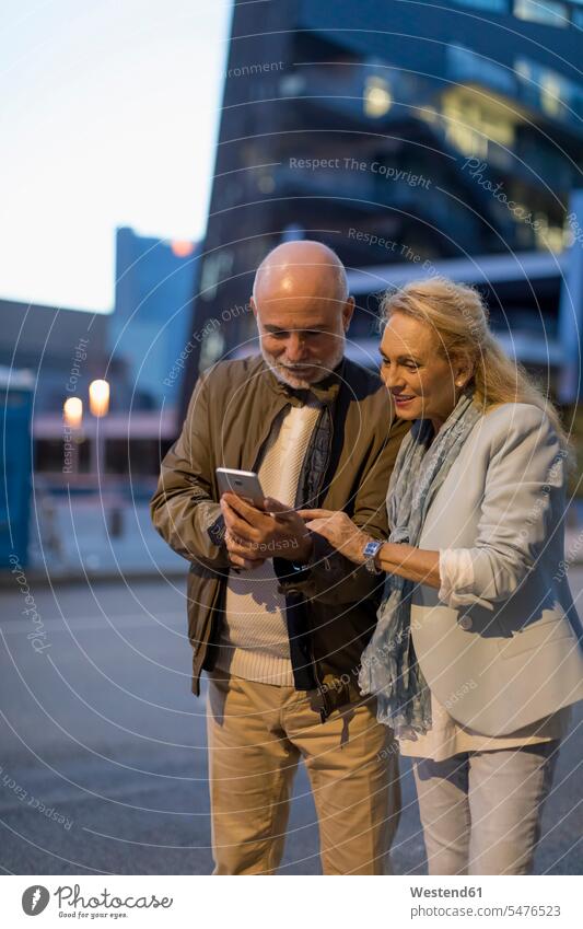 Spain, Barcelona, senior couple sharing cell phone in the city at dusk share mobile phone mobiles mobile phones Cellphone cell phones atmosphere atmospheric