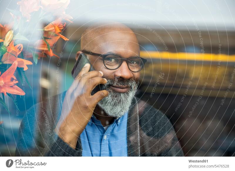 Portrait of smiling man on the phone behind windowpane portrait portraits call telephoning On The Telephone calling smile window glass window glasses
