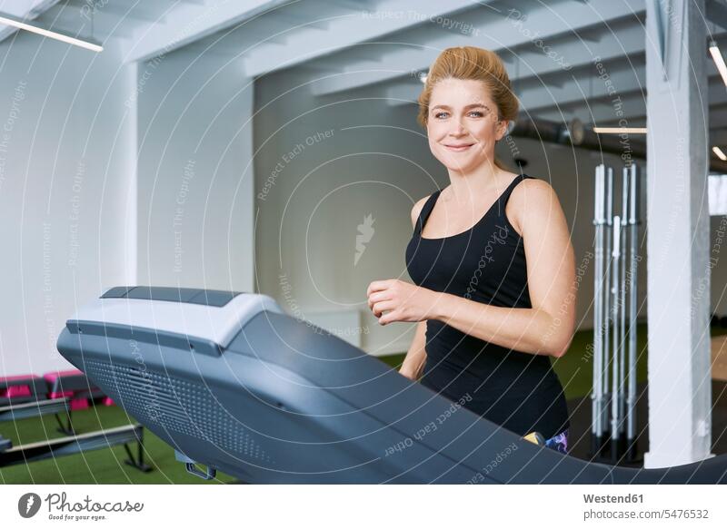 Portrait of smiling woman on treadmill at gym portrait portraits females women gyms Health Club smile Treadmills running machine Adults grown-ups grownups adult