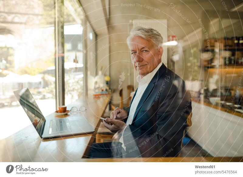Portrait of senior businessman with cell phone and laptop in a cafe business life business world business person businesspeople Business man Business men