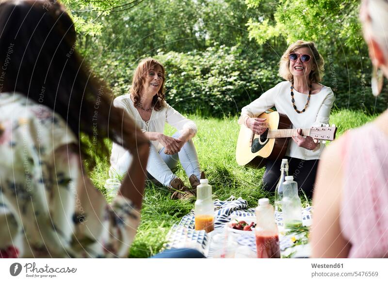 Group of women with guitar having fun at a picnic in park parks female friends guitars Fun funny Picnic picnicking woman females happiness happy mate friendship