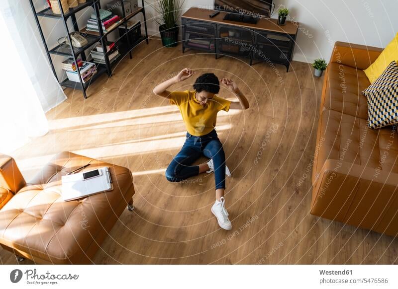 Excited young woman sitting on the floor at home human human being human beings humans person persons celibate celibates singles solitary people solitary person
