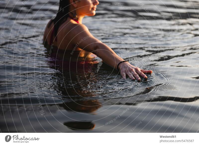 Hand of young woman touching the water surface in a lake lakes hand human hand hands human hands feeling females women waters body of water people persons