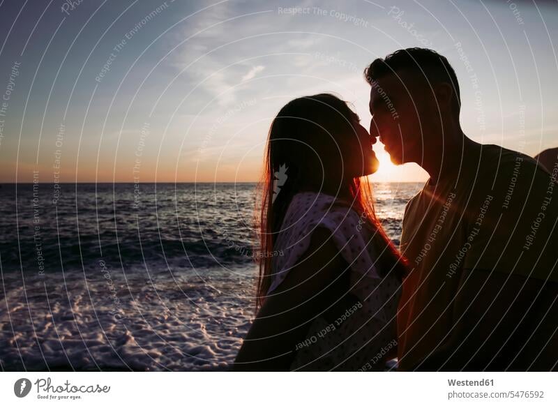 Young couple kissing each other at the beach during sunset towels in the evening Late Evening enjoy enjoyment indulgence indulging savoring Emotions Feeling