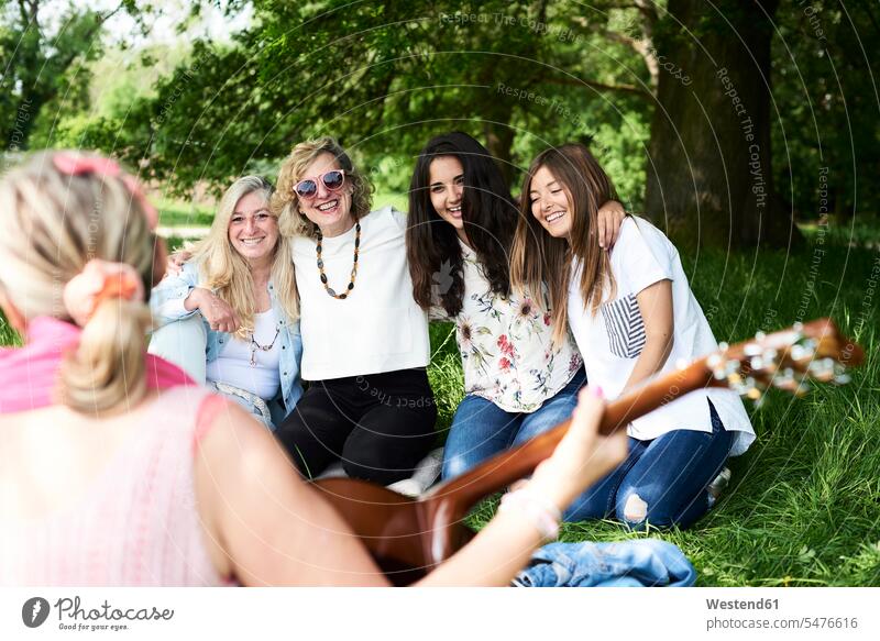 Group of women with guitar having fun at a picnic in park Fun funny woman females Picnic picnicking parks female friends guitars happiness happy Adults