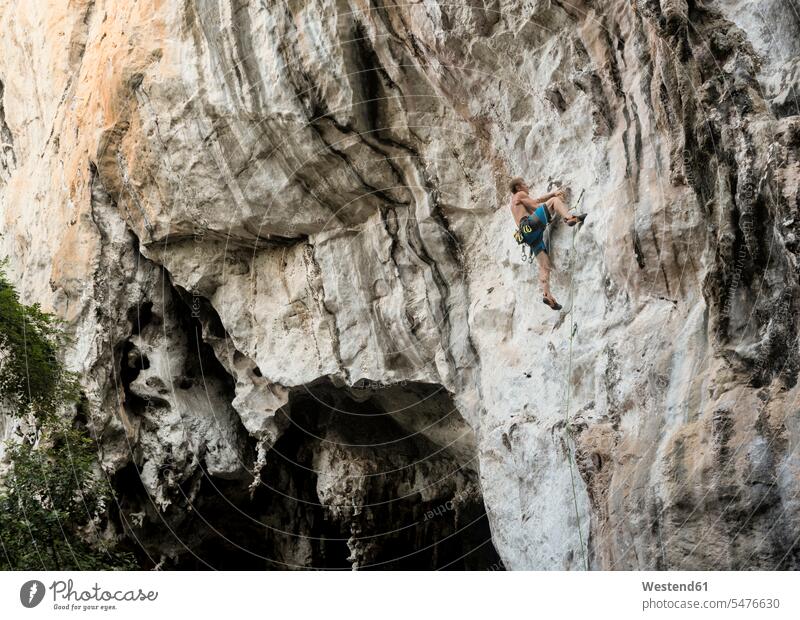 Thailand, Krabi, Railay Beach, barechested climber in rock wall rock climber rock face escarpment rocks climbing climbing up swarm up climbs free climbing