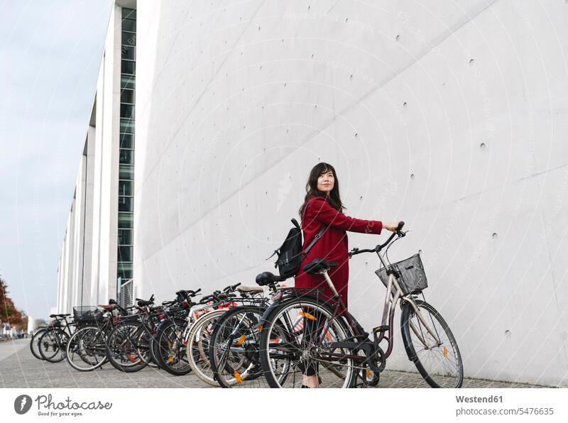 Businesswoman taking bicycle in the background of modern building business life business world business person businesspeople business woman business women