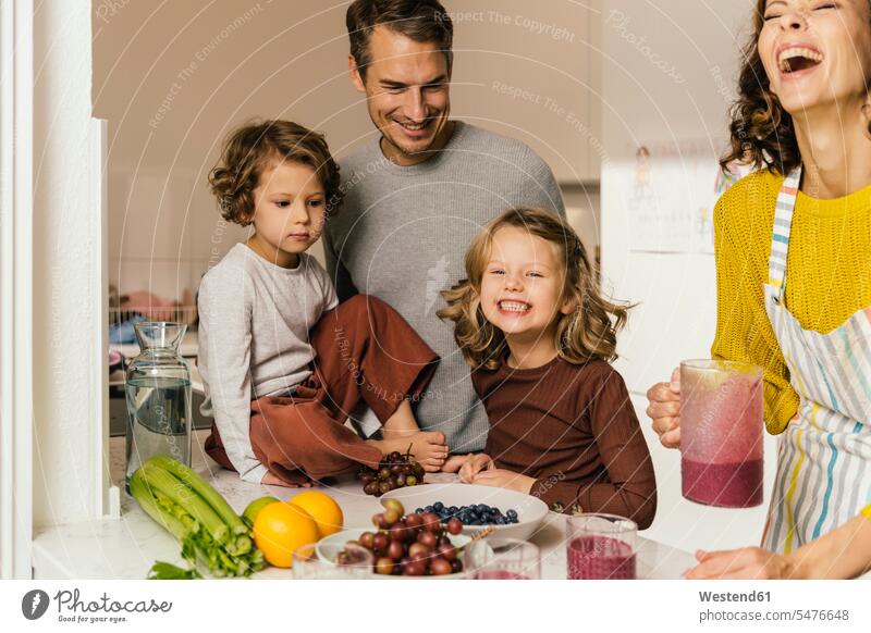 Happy family making a smoothie in kitchen housewives Drinking Glass Drinking Glasses dish dishes Plates smile delight enjoyment Pleasant pleasure Cheerfulness