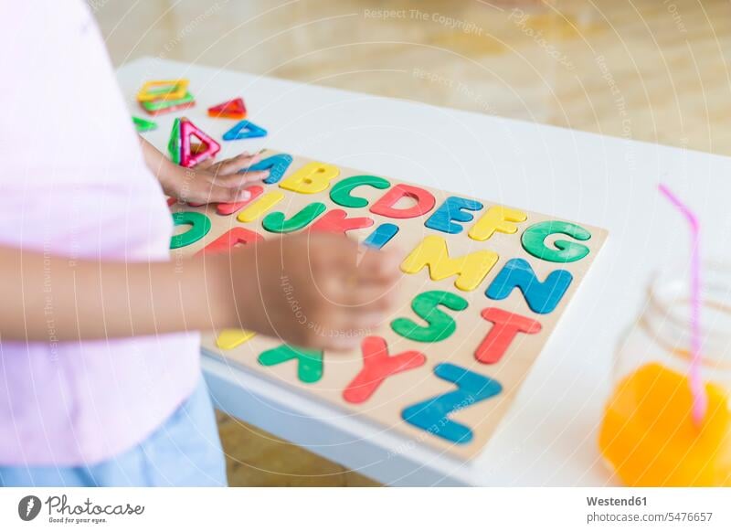 Close-up of girl playing with alphabet learning game on table human human being human beings humans person persons Mixed Race mixed race ethnicity