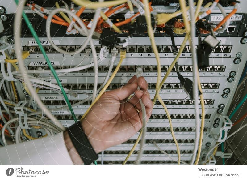 Close-up of hand plugging in cable in data center rack color image colour image indoors indoor shot indoor shots interior interior view Interiors working