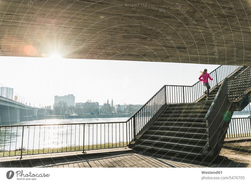 Young woman running up stairs at a river females women upwards stairway River Rivers Jogging Adults grown-ups grownups adult people persons human being humans